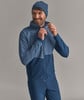 Ein Mann in einer blauen Jacke und Mütze schließt den Reißverschluss.
