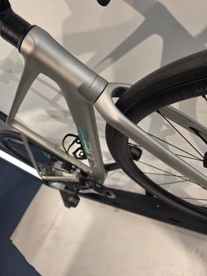Detail des hinteren Teils eines silbernen Rennrads mit einem Laufrad.