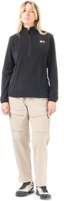 Frau in schwarzem Fleece-Pullover und beiger Cargohose.