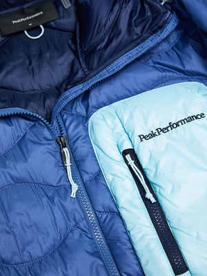 Detail einer Peak Performance Jacke mit blauen und hellblauen Steppnähten und Reißverschlüssen.