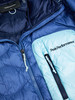 Detail einer Peak Performance Jacke mit blauen und hellblauen Steppnähten und Reißverschlüssen.