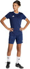 Eine Frau in einem dunkelblauen Fußballtrikot und Shorts mit weißen Socken und Fußballschuhen.
