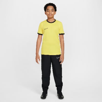 Junge in gelbem T-Shirt und schwarzer Hose mit Nike-Logo. Junge in gelbem T-Shirt und schwarzer Hose mit Nike-Logo.