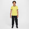 Junge in gelbem T-Shirt und schwarzer Hose mit Nike-Logo.