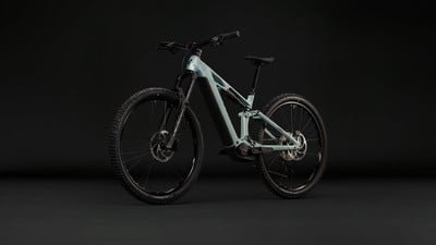 Ein mintgrünes Fullsuspension-E-Bike mit schwarzen Details vor dunklem Hintergrund. Ein mintgrünes Fullsuspension-E-Bike mit schwarzen Details vor dunklem Hintergrund.