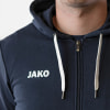 Detail eines Mannes in einem dunkelblauen Kapuzenpullover mit weißem JAKO-Logo.