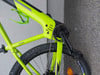 Grüner E-Bike-Rahmen mit Kette und Kurbeln auf grauem Hintergrund.