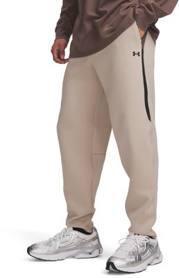 Mann in beigen Jogginghosen und weißen Turnschuhen mit Under Armour Logo. Mann in beigen Jogginghosen und weißen Turnschuhen mit Under Armour Logo.