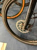Detail eines Mountainbikes mit Scheibenbremse und orangefarbenem Reifen.