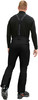 Ein Mann in schwarzer Skihose und Rollkragenpullover mit Hosenträgern.