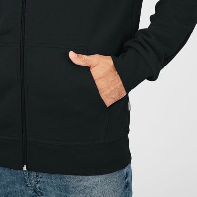Ein Mann steckt seine Hand in die Tasche eines schwarzen Hoodies. Ein Mann steckt seine Hand in die Tasche eines schwarzen Hoodies.