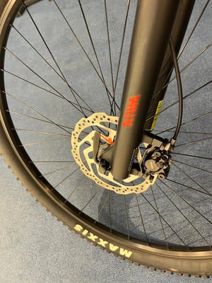 Detail eines Mountainbike-Vorderrads mit Scheibenbremse und Maxxis-Logo. Detail eines Mountainbike-Vorderrads mit Scheibenbremse und Maxxis-Logo.