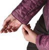 Eine Hand passt den Saum des Ärmels einer gesteppten weinroten Jacke an.