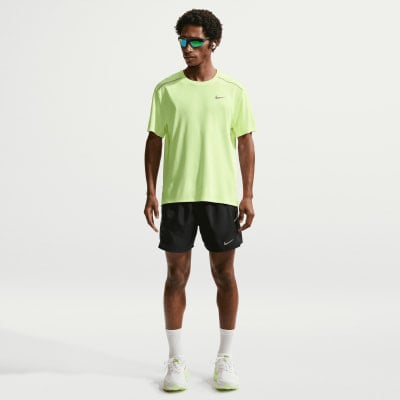 Ein Mann in einem neongrünen T-Shirt und schwarzen Shorts mit Turnschuhen. Ein Mann in einem neongrünen T-Shirt und schwarzen Shorts mit Turnschuhen.