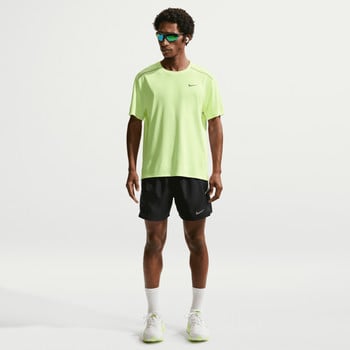 Ein Mann in einem neongrünen T-Shirt und schwarzen Shorts mit Turnschuhen.