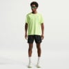 Ein Mann in einem neongrünen T-Shirt und schwarzen Shorts mit Turnschuhen.
