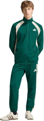 Ein Mann in einem grünen Adidas Trainingsanzug mit beigen Streifen und Sneakern. Ein Mann in einem grünen Adidas Trainingsanzug mit beigen Streifen und Sneakern.