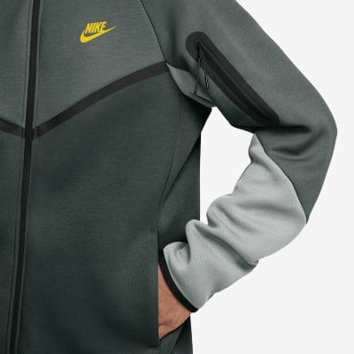 Graue Nike Tech Fleece Herrenjacke mit gelbem Logo und schwarzen Details.