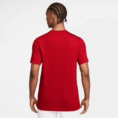 Ein Mann in einem roten kurzärmeligen T-Shirt und weißer Hose, von hinten gesehen.