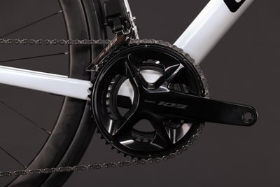Detail des Shimano 105 Kettenblatts an einem weißen Fahrrad mit Kette. Detail des Shimano 105 Kettenblatts an einem weißen Fahrrad mit Kette.