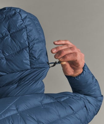 Ein Mann zieht die Kapuze seiner Jacke mit einem Kordelzug enger.
