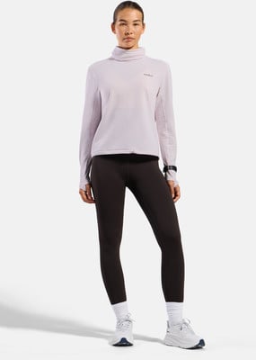 Frau in dunklen Leggings und einem lila Langarm-Rollkragenpullover. Frau in dunklen Leggings und einem lila Langarm-Rollkragenpullover.