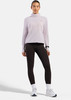 Frau in dunklen Leggings und einem lila Langarm-Rollkragenpullover.