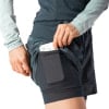 Eine Frau steckt ihr Handy in eine Short mit integrierter Leggings.