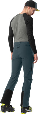 Mann in Skischuhen und Hose mit Dynafit-Logo, von hinten gezeigt. Mann in Skischuhen und Hose mit Dynafit-Logo, von hinten gezeigt.