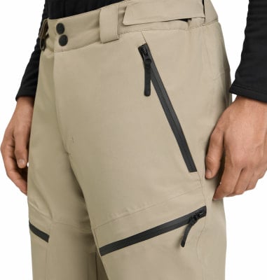 Nahaufnahme einer hellbraunen Hose mit schwarzen Reißverschlüssen und Knöpfen. Nahaufnahme einer hellbraunen Hose mit schwarzen Reißverschlüssen und Knöpfen.