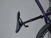 Schwarze Sattelstütze mit rotem Licht am Fahrrad vor einer grauen Wand.