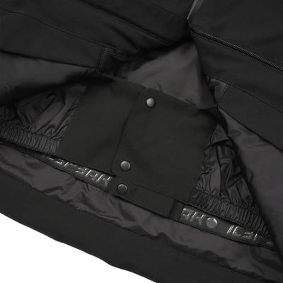 Detail einer schwarzen Hose mit elastischem Innenbund und Druckknopfverschluss.
