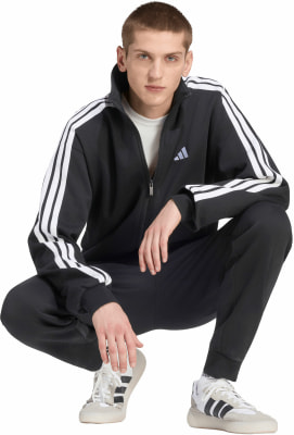 Ein Mann im schwarzen Adidas Trainingsanzug mit weißen Streifen an den Ärmeln. Ein Mann im schwarzen Adidas Trainingsanzug mit weißen Streifen an den Ärmeln.