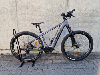 Graues Genesis E-Bike auf einem Ständer vor einer Wand.