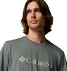 Ein Mann mit langen braunen Haaren trägt ein graues T-Shirt mit Columbia-Logo.