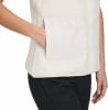 Damen-Weste aus cremefarbenem Fleece mit weißer Tasche und schwarzer Hose.
