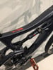 Detail eines Mountainbike-Rahmens mit Dämpfer und orangefarbenem Pedal.