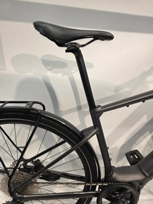 Detail des Sattels und des hinteren Teils eines schwarzen E-Bikes mit Schutzblech und Gepäckträger. Detail des Sattels und des hinteren Teils eines schwarzen E-Bikes mit Schutzblech und Gepäckträger.