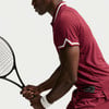 Tennisspieler im roten Hemd mit weißem Kragen hält Schläger.