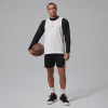 Ein Mann hält einen Basketball und trägt Jordan Sportkleidung.