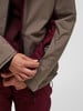 Nahaufnahme einer Jacke mit einer Hand, die einen Ärmelreißverschluss schließt.