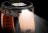 Eine Smartwatch mit orangefarbenem Armband und eingeschalteter Taschenlampe.