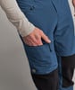Eine Hand greift in die blaue Hosentasche mit schwarzen Einsätzen.