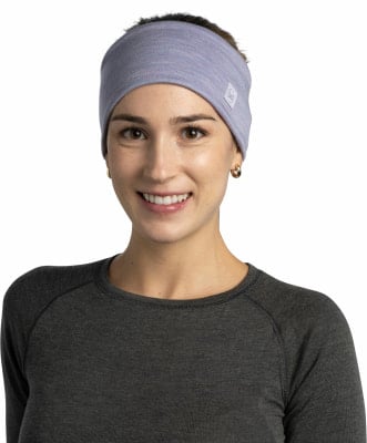 Eine Frau mit einem lila Stirnband und einem dunklen Shirt lächelt in die Kamera.