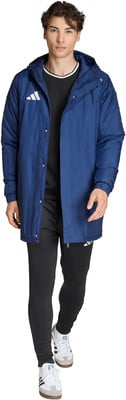 Ein Mann in einer dunkelblauen Kapuzenjacke und schwarzer Trainingshose mit weißen Schuhen.
