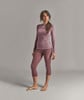 Eine Frau in einem weinroten Thermo-Langarmshirt und Dreiviertel-Leggings.