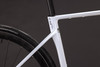 Detail eines weißen Carbon-Fahrradrahmens mit der Aufschrift C62 und einem Reifen.