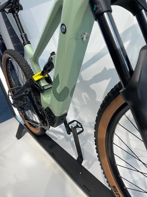Ein grünes E-Bike mit Federung und Dämpfer steht auf einem schwarzen Ständer. Ein grünes E-Bike mit Federung und Dämpfer steht auf einem schwarzen Ständer.