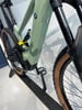 Ein grünes E-Bike mit Federung und Dämpfer steht auf einem schwarzen Ständer.
