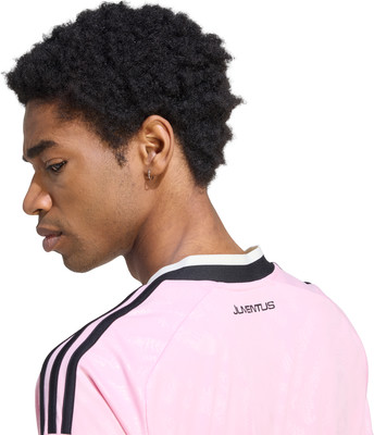 Ein Mann mit lockigem Haar trägt ein pinkes Trikot mit schwarzen Streifen. Ein Mann mit lockigem Haar trägt ein pinkes Trikot mit schwarzen Streifen.